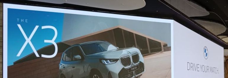 BMW X3 ad on a large LED display in a tech park atrium
