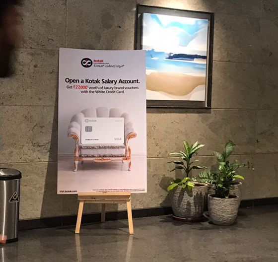Kotak salary account standee on an easel in a corridor