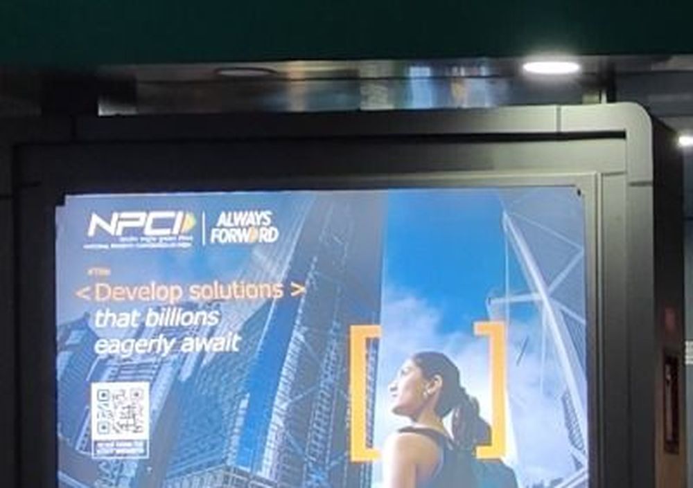 NPCI ad on a backlit panel at a campus entrance