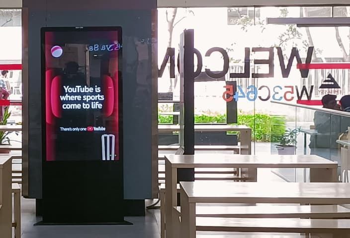 YouTube ad on a digital screen in a tech park food court