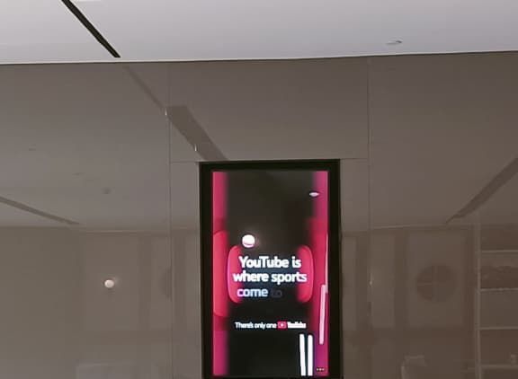 YouTube ad on a wall-mounted digital screen in a lobby